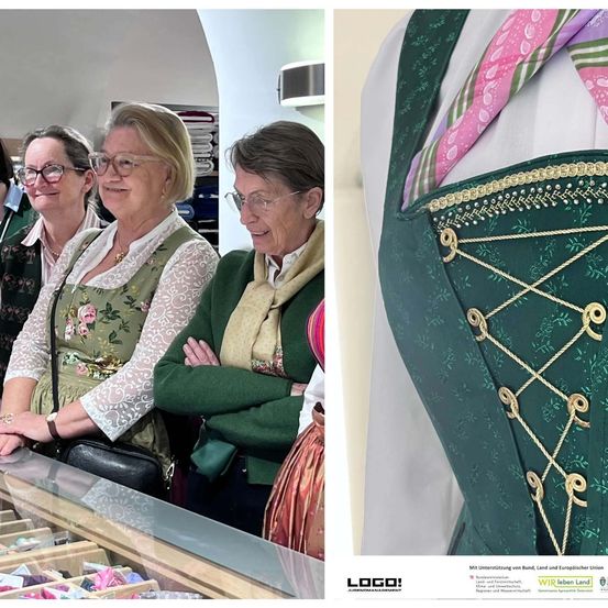 Drei Frauen mit Brille und Blumenkleidern stehen neben einer Vitrine. Rechts ein traditionelles grünes Schürzen mit goldenen Schnüren.