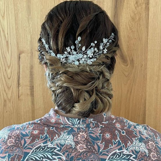 Eine Frau mit braunen Haaren in einem geflochtenen Dutt mit einem Kristallhaarzubehör auf dem Rücken.