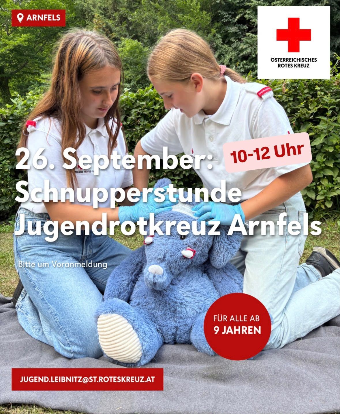 Zwei junge Mädchen in weißen Rotkreuz-Uniformen üben Erste Hilfe an einem blauen Kuscheltier. Das Event ist für den 26. September von 10 bis 12 Uhr geplant.