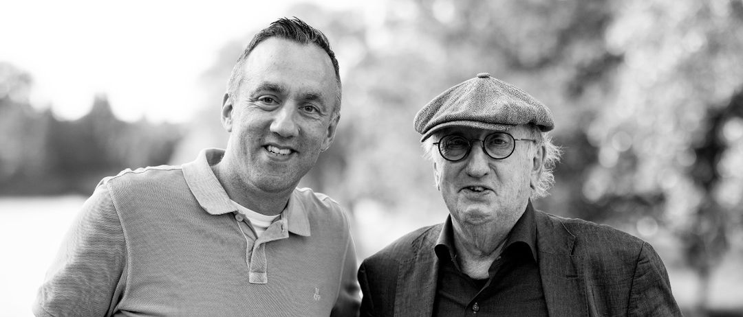 Ein Schwarz-Weiß-Foto von zwei Männern, die nah beieinander stehen, lächeln und möglicherweise für ein Foto posieren.