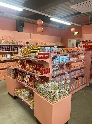 Ein Laden mit pastellrosa Regalen, gefüllt mit verschiedenen verpackten Artikeln. Dekorationen wie Laternen hängen von der Decke.