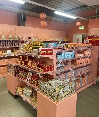 Ein Laden mit pastellrosa Regalen, gefüllt mit verschiedenen verpackten Artikeln. Dekorationen wie Laternen hängen von der Decke.