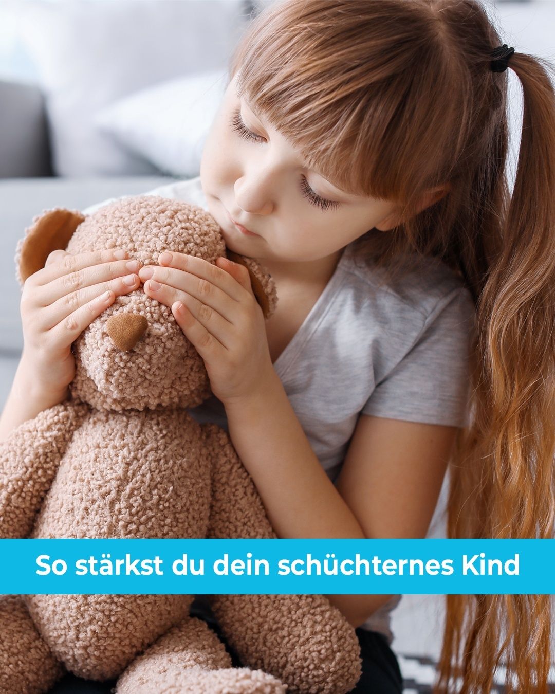 Ein junges Mädchen umarmt einen braunen Teddybären mit geschlossenen Augen, was auf einen Moment des Trostes und der Sicherheit hinweist. Sie trägt ein graues T-Shirt und sitzt auf einer Couch. Ein blauer Text-Overlay lautet 'So stärkst du dein schüchternes Kind.'