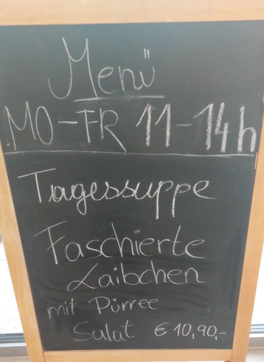 A blackboard shows the menu, open Monday to Friday from 11 AM to 2 PM, including 'Tagessuppe' and 'Faschierte Laibchen mit Purree.'