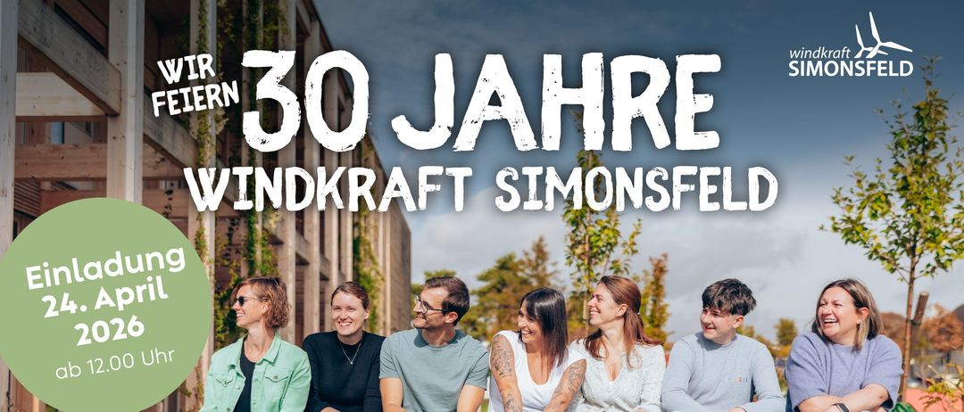Eine Gruppe von Menschen sitzt gemeinsam auf einer Betonbank in einem Grasbereich. Die Worte '30 Jahre Windkraft Simonsfeld' sind prominent darüber angebracht.
