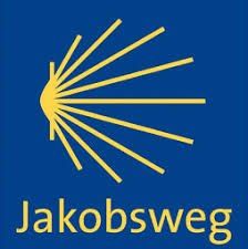 Ein blauer Hintergrund zeigt ein gelbes Sonnenburst-Logo mit strahlenden Linien über dem Wort 'Jakobsweg' in gelber, serifenloser Schrift.