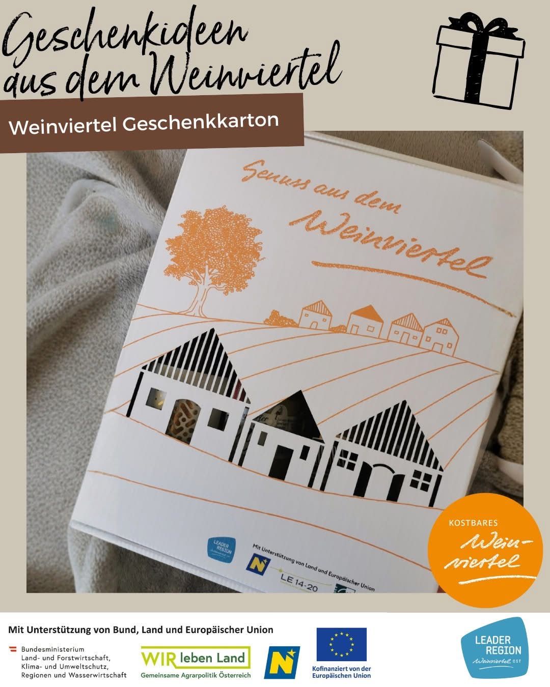 Eine Karte mit dem Titel 'Weinviertel Geschenkkarton' zeigt ein Design von Häusern, einem Baum und einer Landschaft. Die Karte enthält Text auf Deutsch und ein Logo.