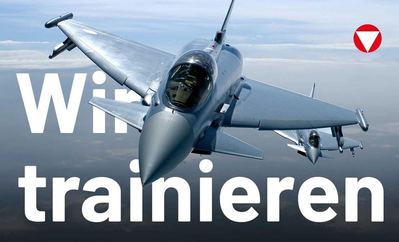 Ein Kampfjet fliegt durch den Himmel, wobei das Wort 'Training' im Vordergrund deutlich sichtbar ist. Der Jet hat ein schlankes Design, und seine Kabine ist sichtbar.