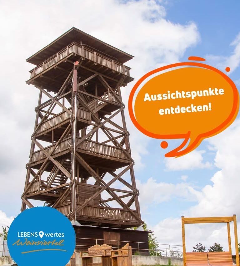 Ein hölzerner Aussichtsturm mit mehreren Ebenen und Treppen, unter einem bewölkten Himmel. Eine Sprechblase enthält den Text 'Aussichtspunkte entdecken!'. Das Logo 'Lebenswertes Weinviertel' ist sichtbar.