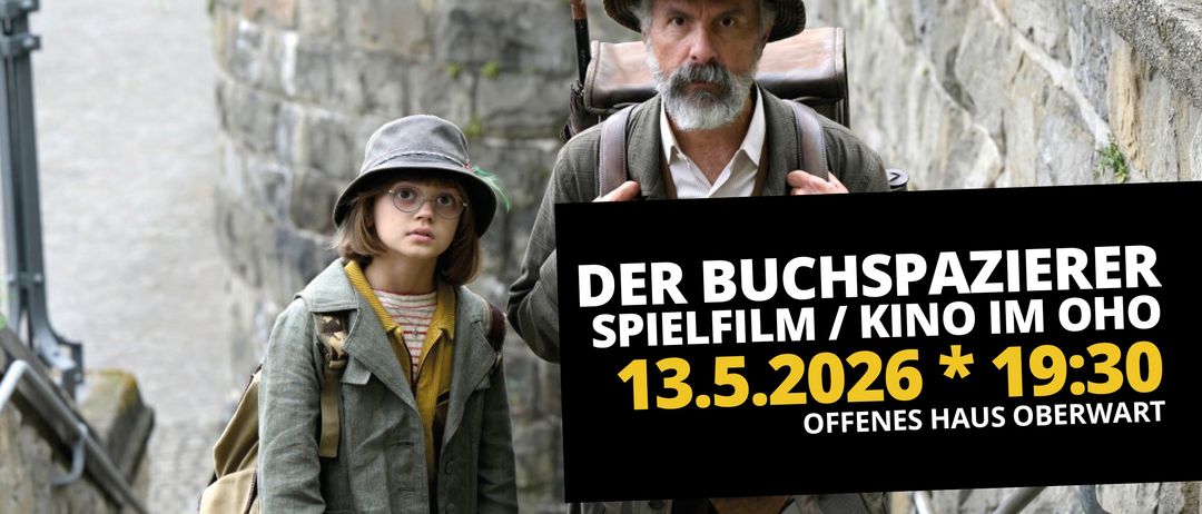 Ein alter Mann und ein junges Mädchen, beide mit Hüten, stehen vor einer Steinmauer. Der Mann hält ein Schild mit der Aufschrift 'Der Buchspielfilm / 13.5.2026 OFFNES'.