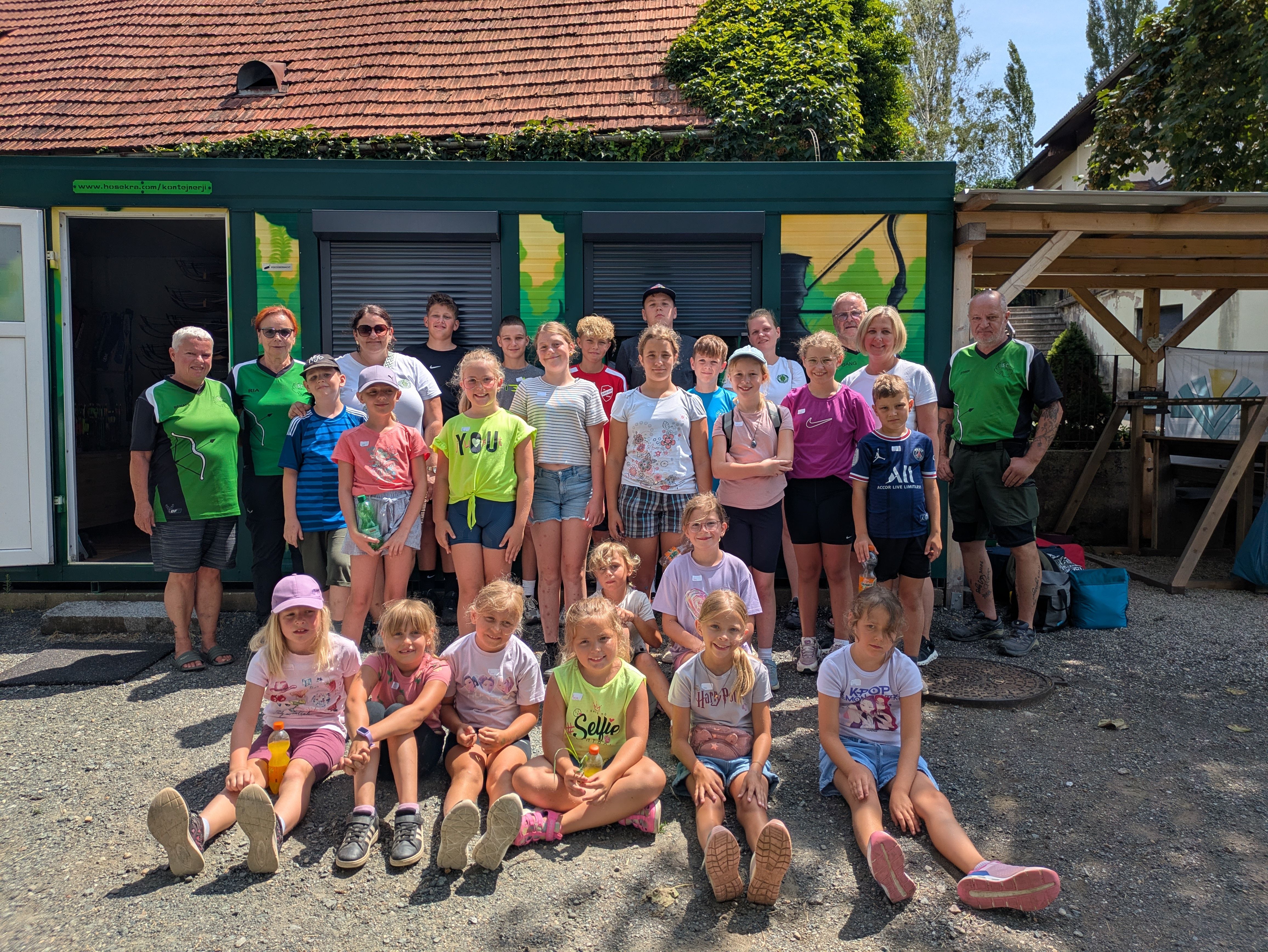 Jugendgruppe mit Betreuern vor einem grünen Container in Österreich