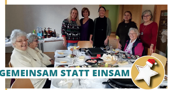 Eine Gruppe von Frauen steht lächelnd um einen festlich gedeckten Tisch herum. Der Tisch ist mit verschiedenen Speisen und Getränken gefüllt. Auf der rechten Seite ist ein Weihnachtsstern zu sehen. Das Bild hat eine festliche Überlagerung mit dem Text 'Gemeinsam statt einsam'.