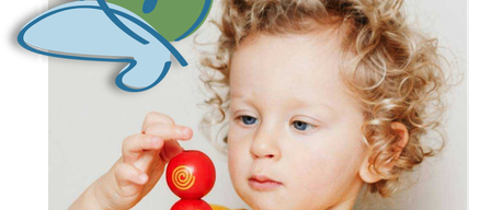 Ein junges Kind mit lockigen Haaren und einem gelben T-Shirt stapelt bunte Ringe.