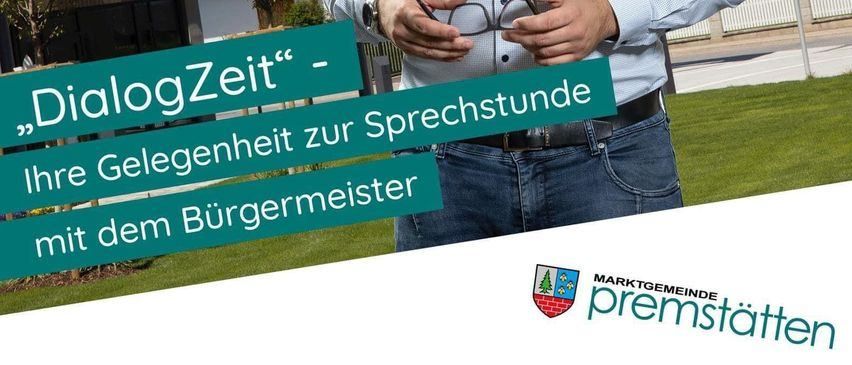 Ein Mann hält ein Schild, das 'DialogZeit - Gelegenheit zum Gespräch mit dem Bürgermeister' vor dem Rathaus zeigt.
