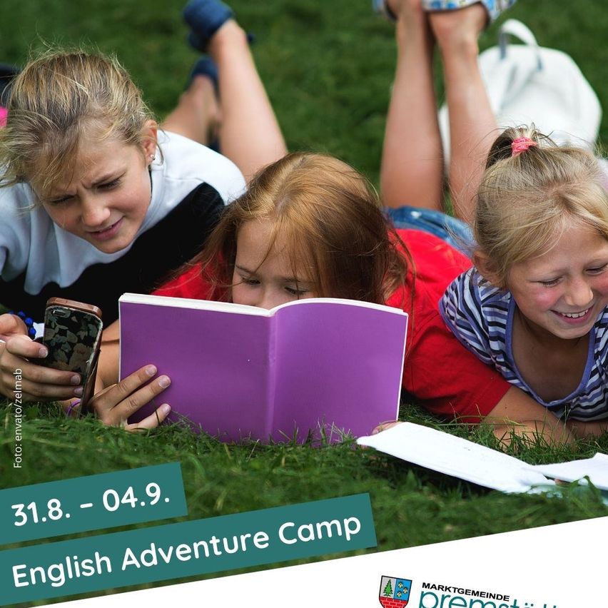 Drei Mädchen liegen auf dem Gras, lesen ein Buch und benutzen ein Handy. Der Text auf dem Bild lautet '31.8. - 04.9. Englisches Abenteuercamp.' Es gibt einen Wasserzeichen, der 'Foto: enviro/zelmab' lautet.