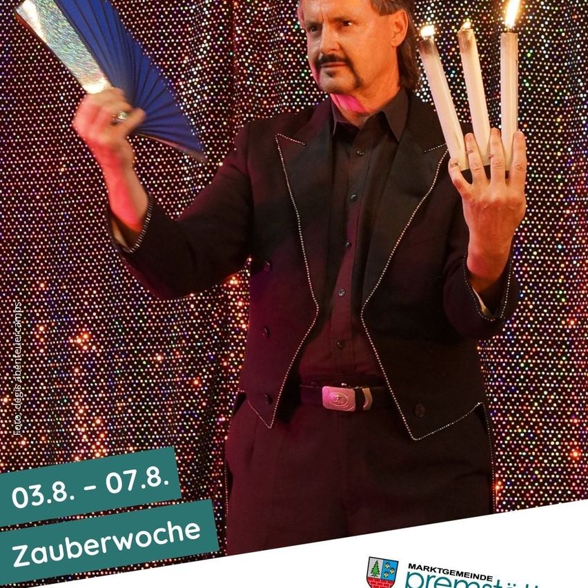 Ein Mann in einem schwarzen Anzug hält einen blauen Fächer und Kerzen in den Händen vor einem bunten Hintergrund. Das Bild hat einen Wasserzeichen mit dem Text Zauberwoche und den Daten 03.8-07.8.