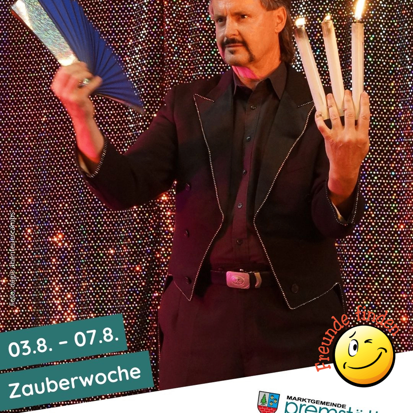 A magician holds four lit candles in his hands. He is wearing a black suit with a belt. The background is a glittering red-orange backdrop with text overlay.