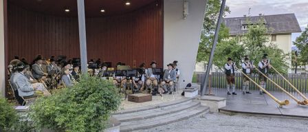 Eine traditionelle Band spielt auf einer Bühne vor Publikum, mit Musikern, die Trompeten und Posaunen spielen.