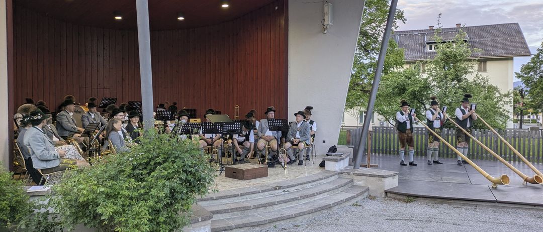 Eine traditionelle Band spielt auf einer Bühne vor Publikum, mit Musikern, die Trompeten und Posaunen spielen.