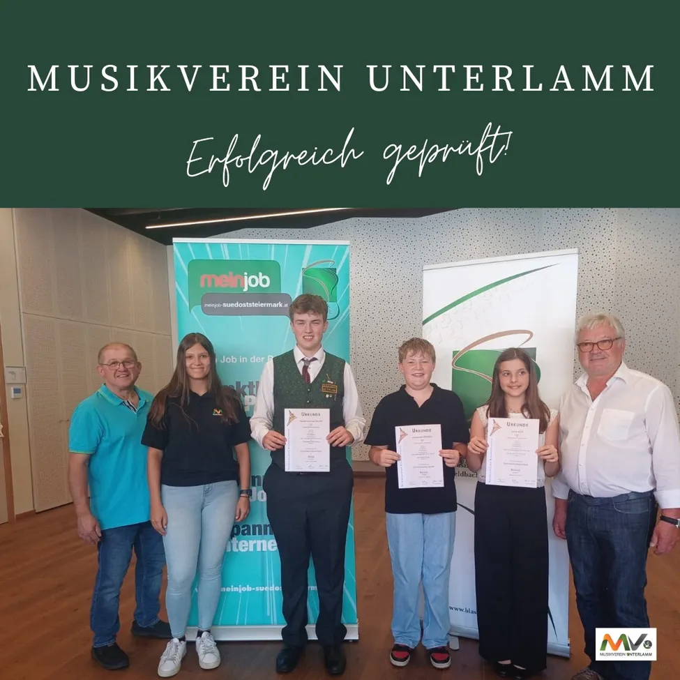 Eine Gruppe von Menschen steht vor einem Banner. Sie halten Urkunden in den Händen. Auf dem Banner steht Musikverein Unterlamm Erfolgreich gepruft.