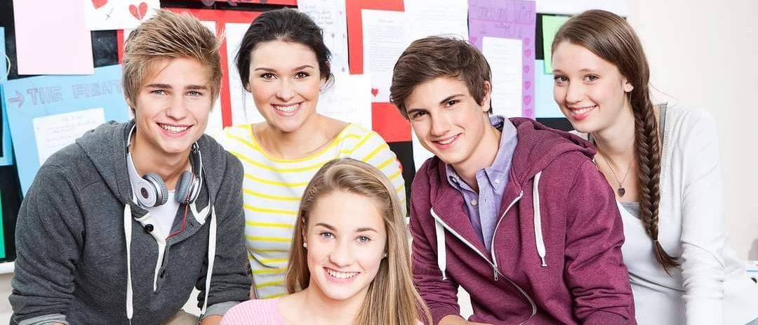 Eine Gruppe von Teenagern posiert für ein Foto vor einer Wand mit Romeo-und-Julia-Plakaten und Herzen.