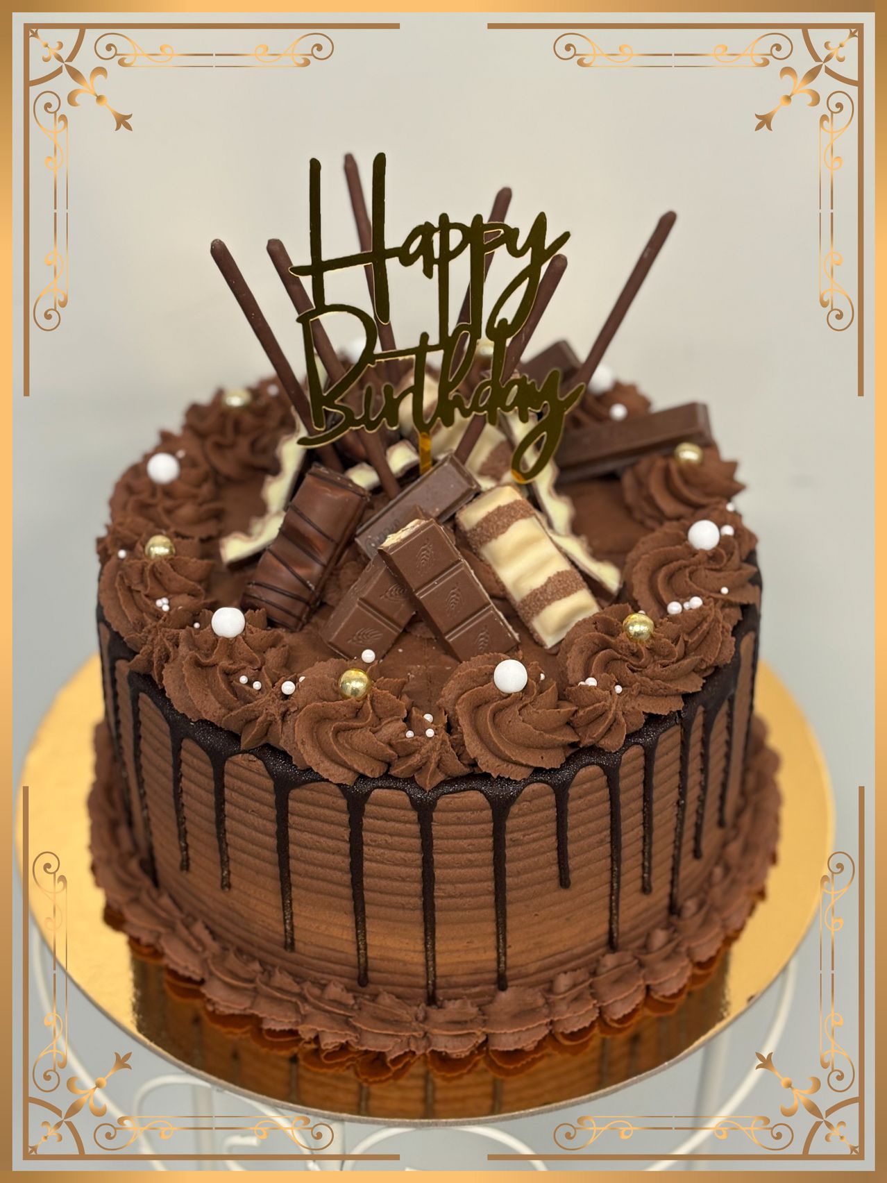 Ein Schokoladenkuchen mit Schokoladenglasur und Schokoladenstücken. Der Kuchen ist mit 'Happy Birthday' auf der Oberseite dekoriert und hat Schokoladentropfen.