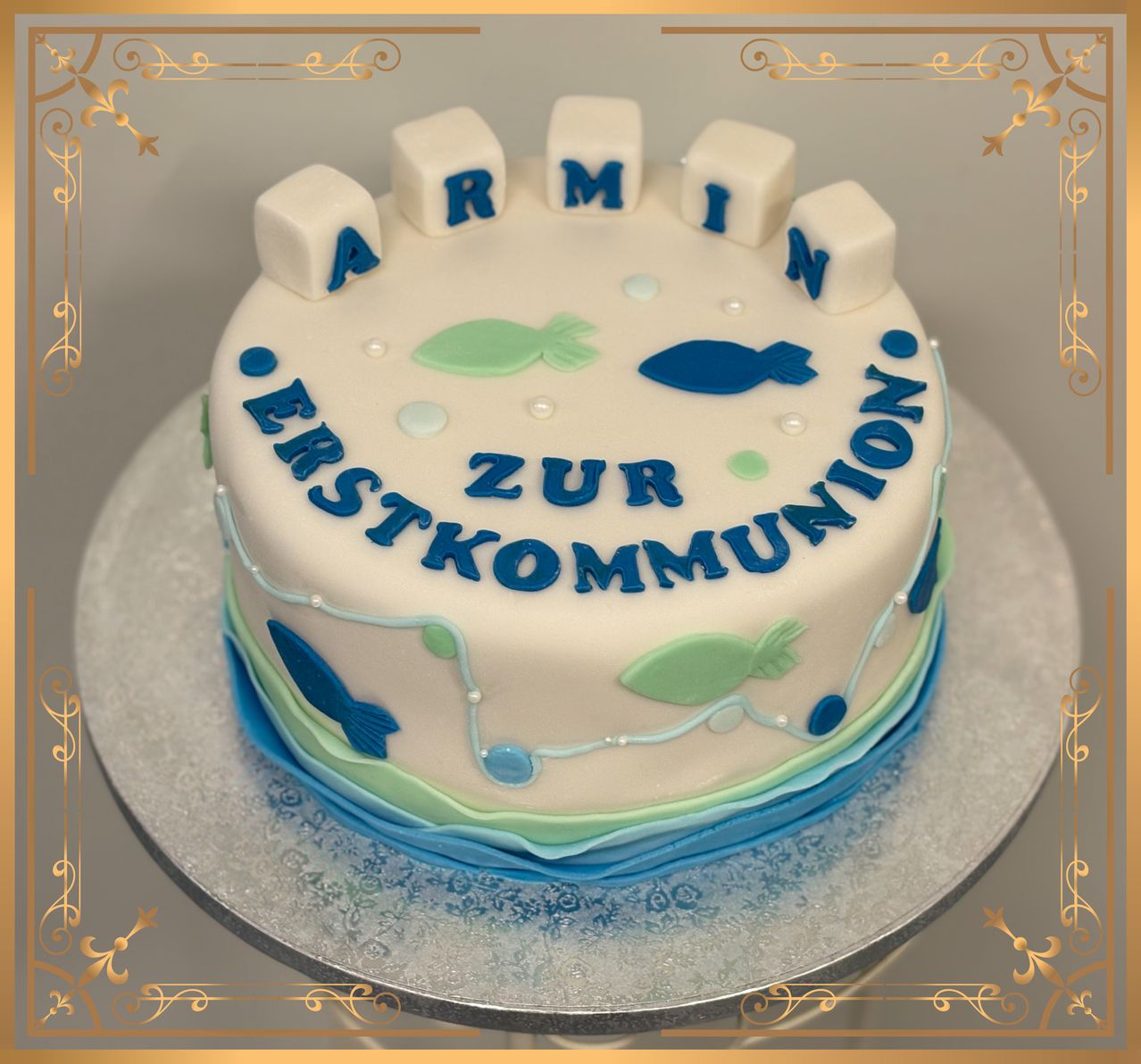 A cake with 'ARMIN' on top, decorated with fish and bubbles, celebrating the first communion.