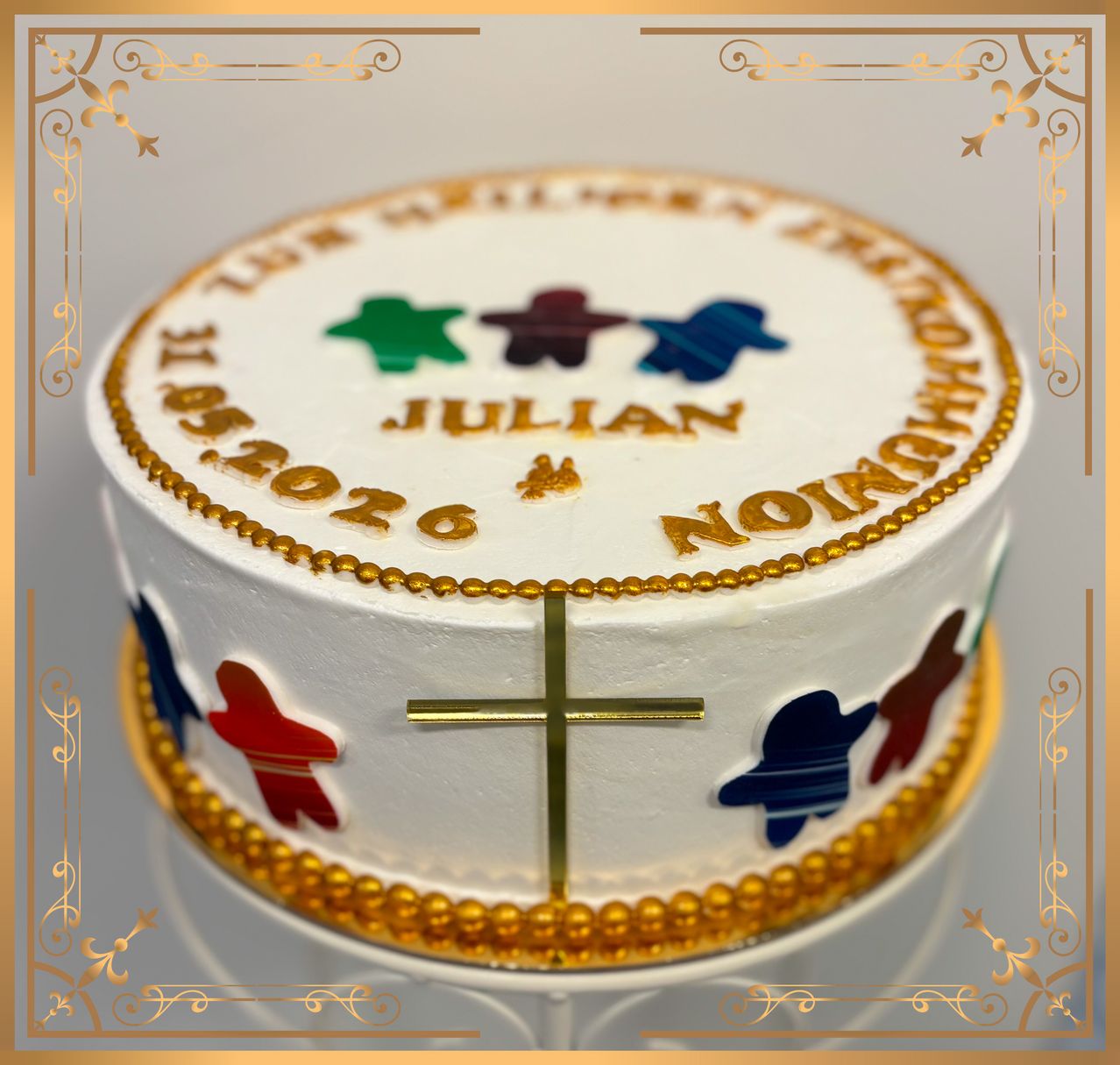 A white cake with gold trim and a gold cross on it, celebrating Julian's 15th birthday on 06/09/2026. The cake is adorned with colorful fish designs.