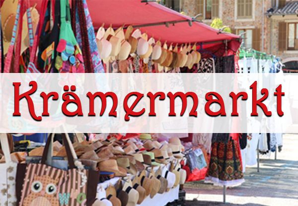Ein Marktstand mit rotem Vordach zeigt verschiedene Hüte und Taschen an Kleiderbügeln. Das Wort Kramermarkt ist prominent angezeigt.