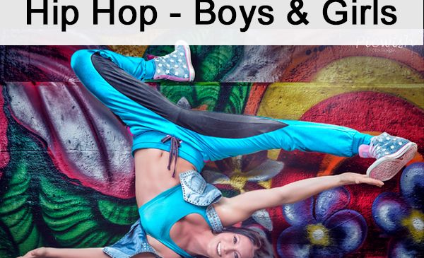 Eine Frau in blauer und schwarzer Trainingskleidung führt einen Handstand gegen eine mit Graffiti bemalte Wand durch und lächelt.