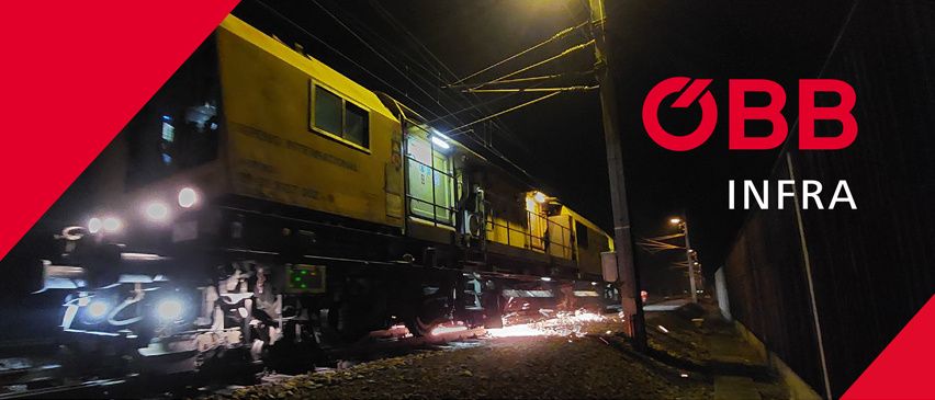 Ein gelber Zug fährt nachts auf den Gleisen. Funken fliegen von der Front. Der Zug hat den Text 0BB Infra.
