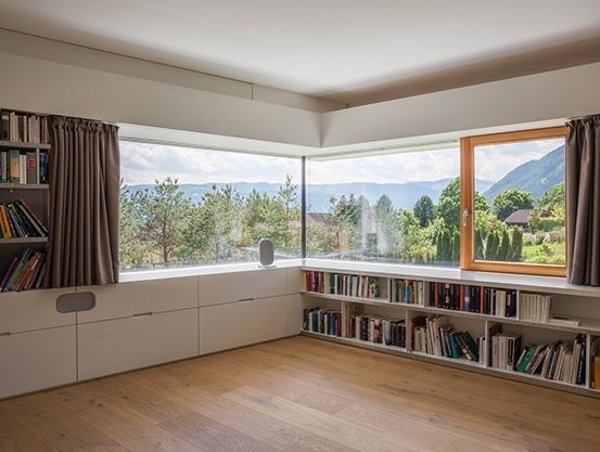 Ein Zimmer mit einer großen Fensterbank, gefüllt mit Büchern, und Blick auf eine Berglandschaft.