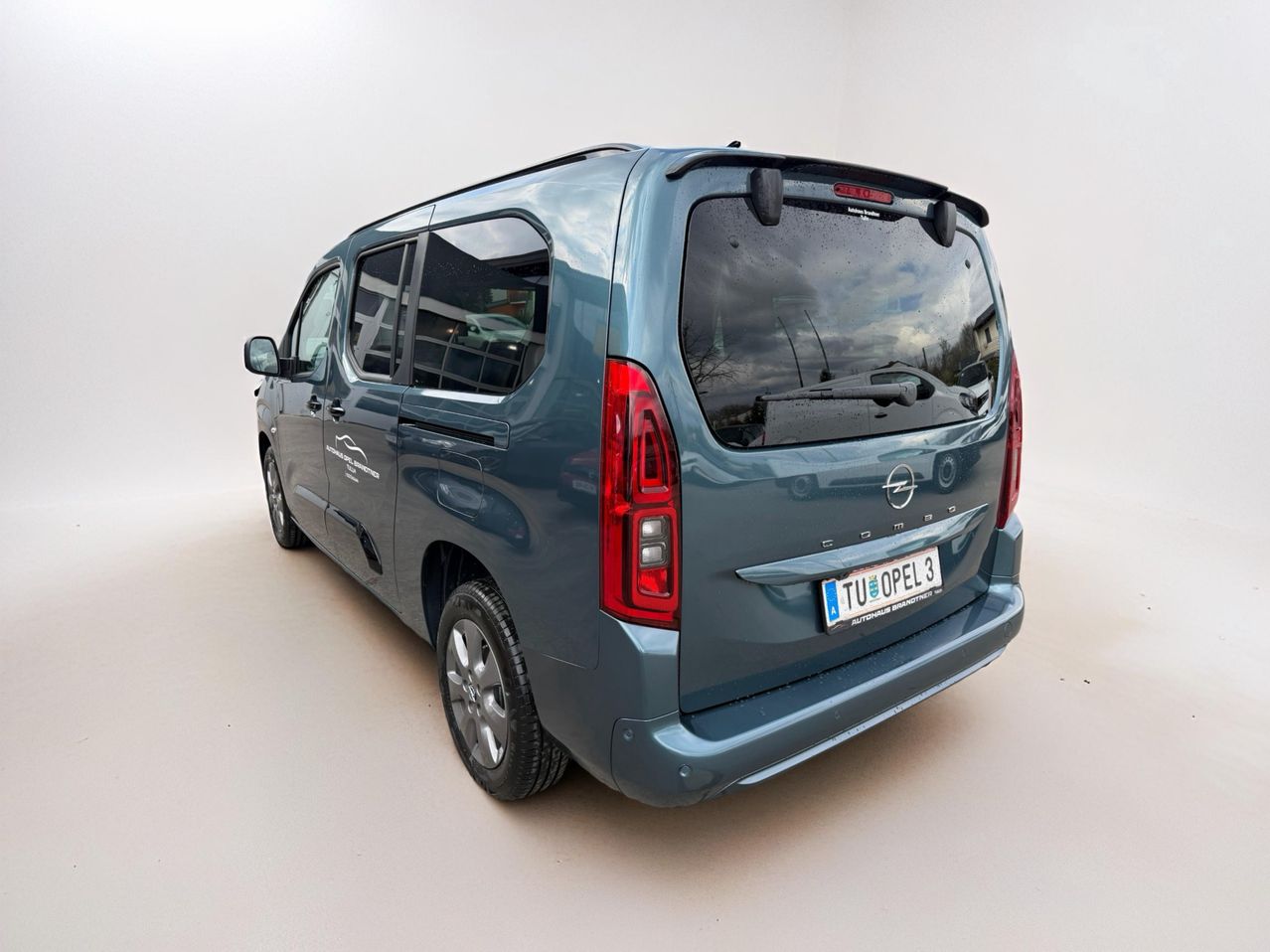Die Rückansicht eines grauen Opel-Fahrzeugs in einer Garage, mit einem Nummernschild, das TU OPEL 3 liest.