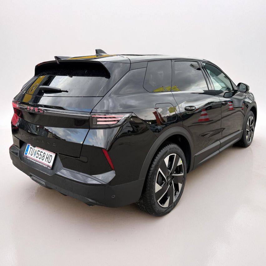 Ein schwarzer SUV mit glänzendem Finish ist drinnen geparkt. Es hat ein Nummernschild mit der Aufschrift 'TU 558 HD' und einen Spoiler auf der Rückseite.