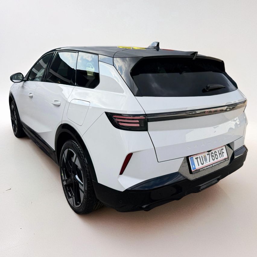 Ein weißer SUV mit schwarzem Dach, Chromleisten und einem Nummernschild mit der Aufschrift 'TU 766 HF' auf der Rückseite, geparkt auf einer weißen Oberfläche.