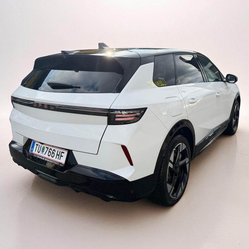 Die Heckansicht eines weißen Opel Elektro-SUVs mit schwarzem Dach, Kennzeichen 'TU 766 HF', schlankem Design und modernen LED-Rückleuchten.