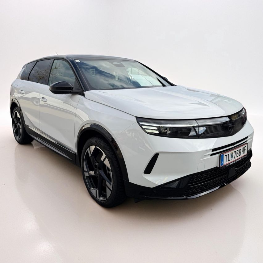 Ein weißer Elektro-SUV mit schlankem Design, auf einer weißen Oberfläche geparkt. Es verfügt über moderne LED-Scheinwerfer, ein Nummernschild TU 766 HF und schwarze Leichtmetallräder.