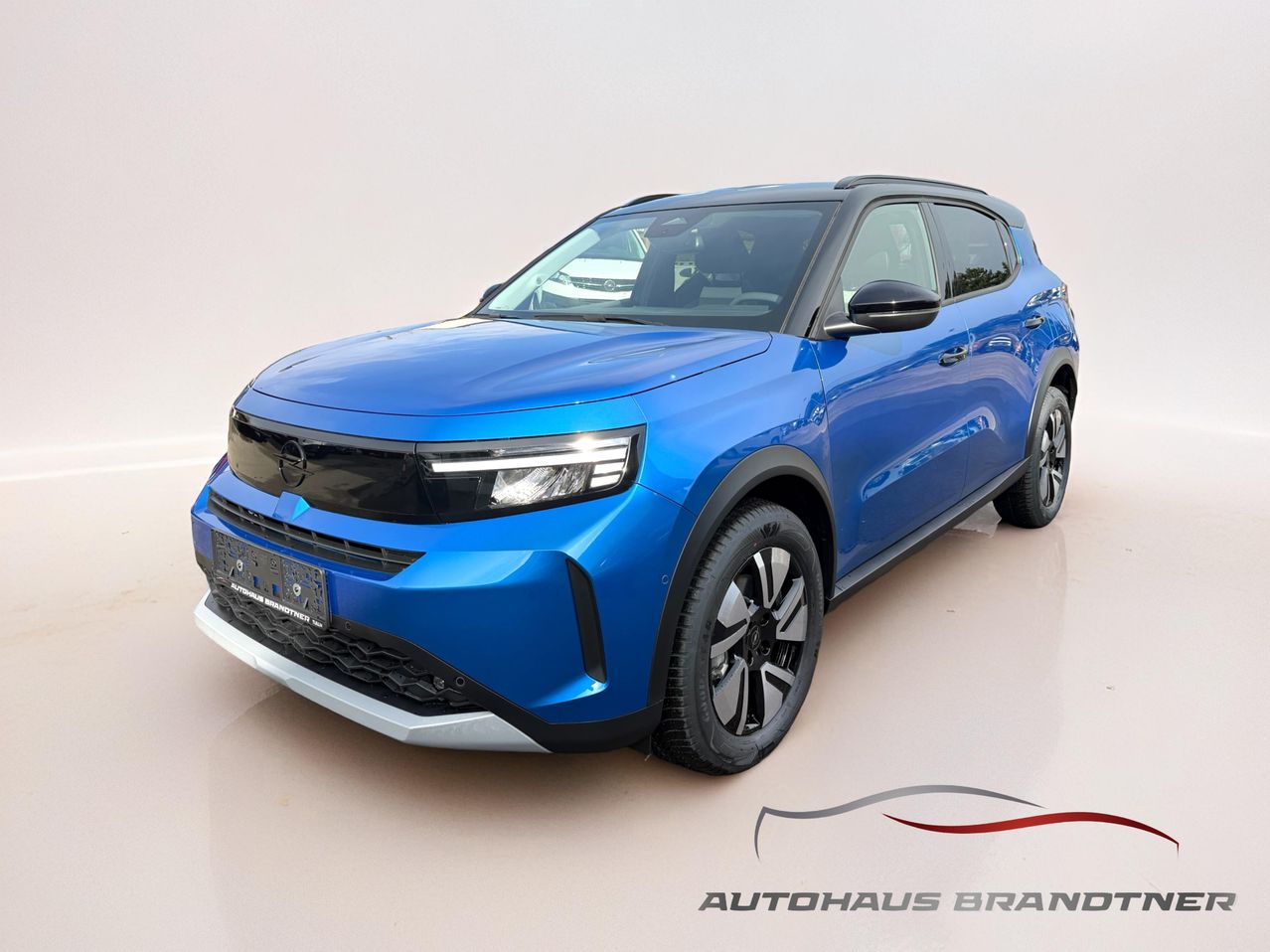 Die Front eines blauen Elektro-SUV mit schlanken Scheinwerfern und einem markanten Kühlergrill, präsentiert auf weißem Hintergrund.