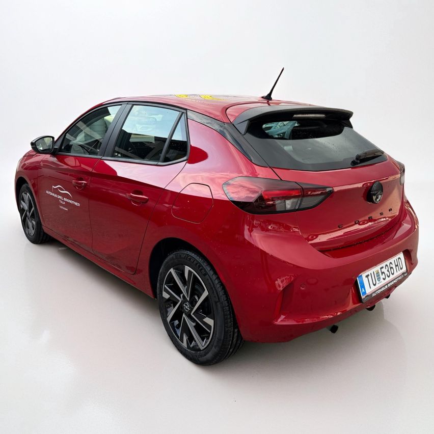 Ein rotes Auto mit dem Kennzeichen TU 536 HD wird auf weißem Hintergrund gezeigt. Es hat einen schwarzen Spoiler hinten, ein schwarzes und silbernes Leichtmetallrad und ein Logo an der Seite.