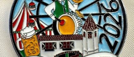 Eine Anstecknadel mit einem Mann, der eine Trommel mit einem Bierkrug und einem Riesenrad im Hintergrund spielt. Die Anstecknadel trägt die Aufschrift 'Herbstfest Rosenheim 2020'.