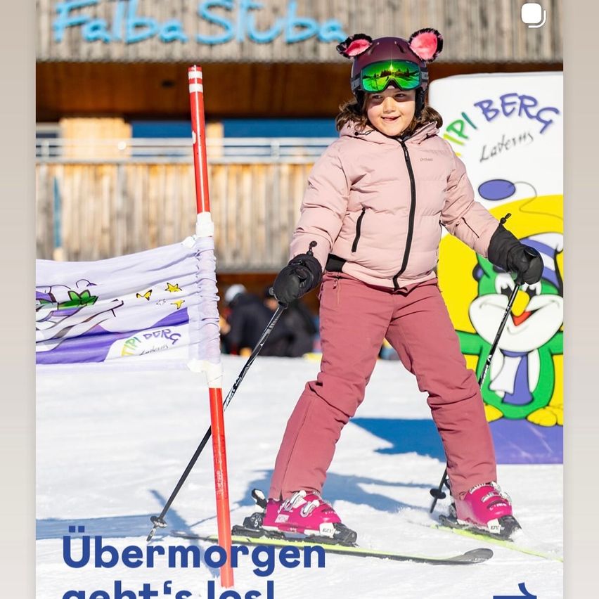 Ein junges Mädchen beim Skifahren mit Skistöcken und einer rosa Jacke an einem sonnigen Tag. Im Hintergrund steht ein Banner mit den Worten 'Ubermorgen geht's los'.