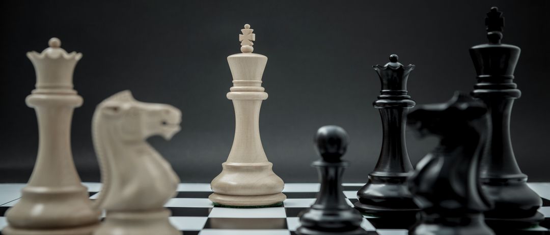 Ein Schachbrett mit einem weißen König in der Mitte, umgeben von schwarzen und weißen Figuren. Der Hintergrund ist dunkel und erzeugt einen Kontrast.