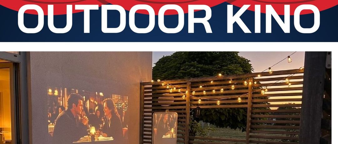 Ein Outdoor-Kino-Event mit Filmprojektion, gemütlichem Aufbau mit Kissen, Kerzen und Popcorn. Ein Baum und ein Zaun mit Lichterketten verstärken die Atmosphäre.