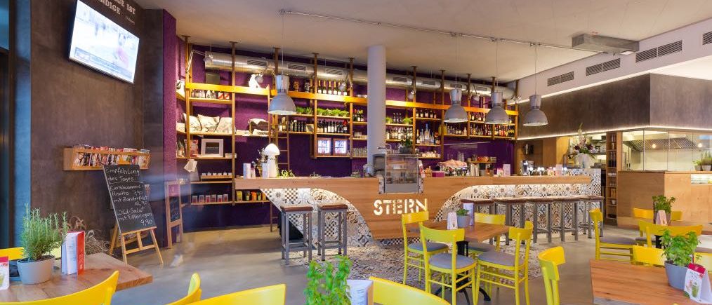 Bild enthält, Indoors, Restaurant, Cafeteria, Chair, Building, Plant, Monitor, Dining Table, Cafe, Bar