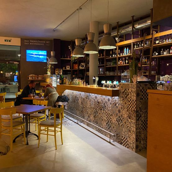 Bild enthält, Bar, Person, Chair, Lamp, Glasses, Monitor, Hat, Cup