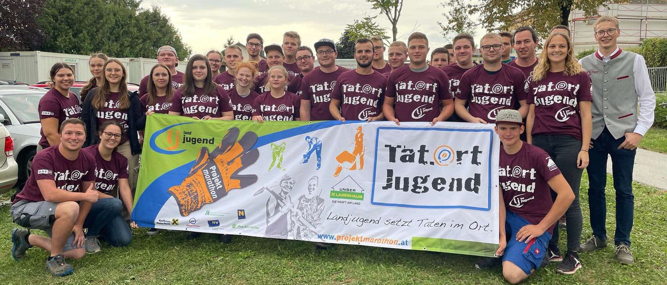 Eine Gruppe junger Menschen posiert mit einem Banner, auf dem 'Tatort Jugend' steht. Sie tragen alle die gleichen T-Shirts.