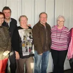 Eine Gruppe von sechs Personen posiert für ein Foto vor einer weißen Wand. Sie alle lächeln und wirken fröhlich.