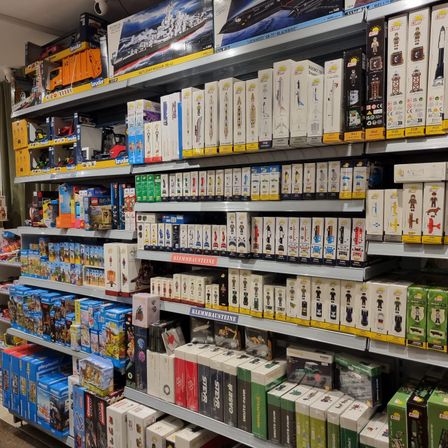 Ein Laden mit einer großen Ausstellung von Spielzeug und Figuren, einschließlich einer großen Box eines Spielzeugschiffs und vieler Schachteln mit Figuren in den Regalen.