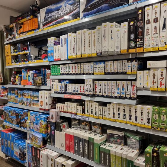 Ein Laden mit einer großen Ausstellung von Spielzeug und Figuren, einschließlich einer großen Box eines Spielzeugschiffs und vieler Schachteln mit Figuren in den Regalen.