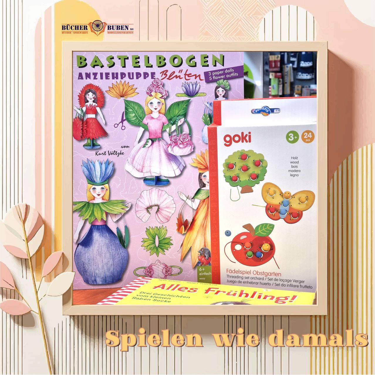 Ein Holzregal zeigt eine Schachtel mit der Aufschrift 'Bastelbogen Anziehpuppe Blinten' mit verschiedenen Papierpuppen und Blumen. Daneben befindet sich eine Schachtel eines Fadenspiel-Obstgartens für Kinder mit Äpfeln und Blumen. Darunter steht der Text 'Alle Frühling!' und 'Spielen wie damals'.